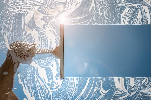 Close-up of a hand holding a sharp blade cutting a blue panel, with a decorative patterned backdrop in the background.